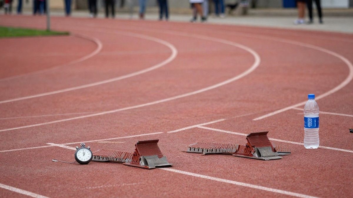 Imagen ilustrativa: pista de atletismo con cronómetro y botella de agua sobre los tacos de salida