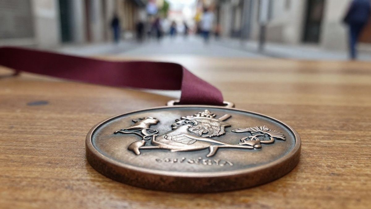 Imagen ilustrativa: primer plano de una medalla metálica con cinta roja sobre una mesa de madera