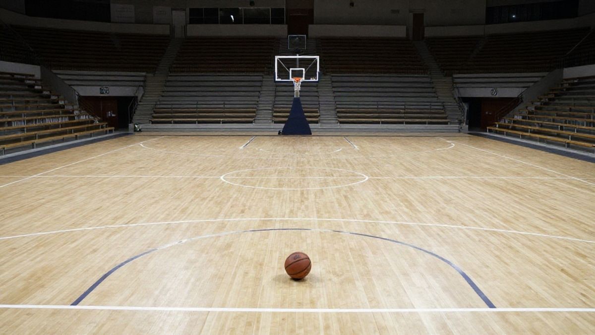 Imagen ilustrativa: cancha de baloncesto genérica con un balón en la línea de tiros libres y gradas vacías