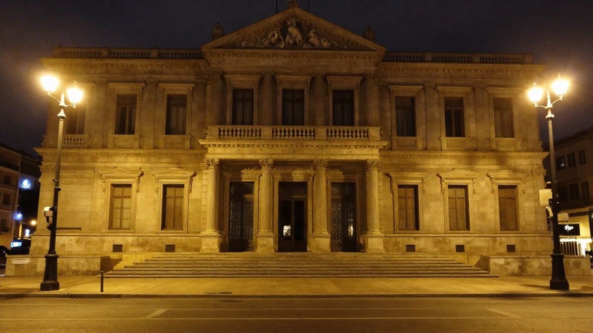 Imagen ilustrativa: fachada de un edificio parlamentario regional iluminado por farolas en horario nocturno