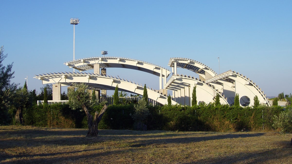 Estructuras curvas de hormigón blanco de la antigua Estufa Fría entre olivos, en el parque Juan Carlos I