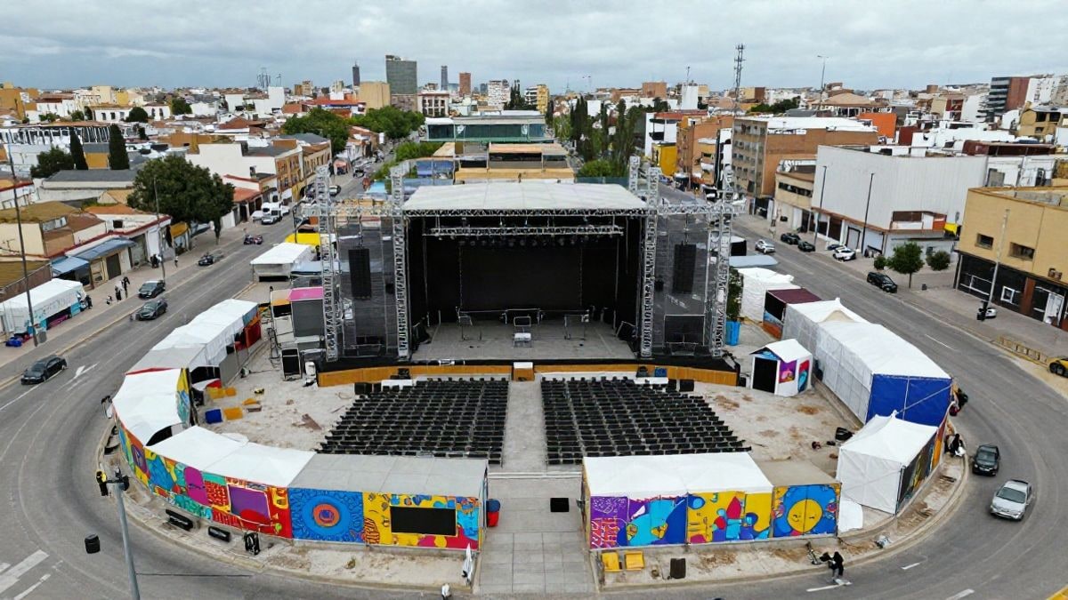 Imagen ilustrativa: vista aérea de un gran recinto de conciertos al aire libre con escenario y pabellones temáticos en una zona industrial.