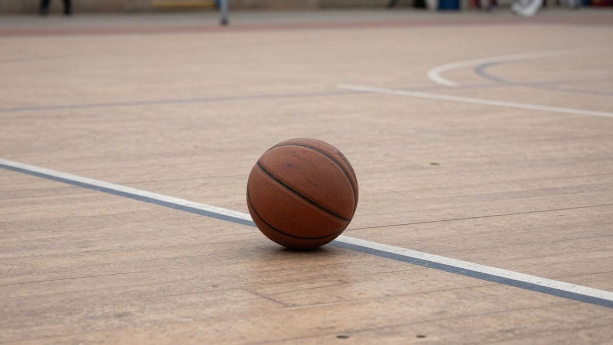 Imagen ilustrativa: detalle del parqué de una cancha de baloncesto con un balón de cuero apoyado