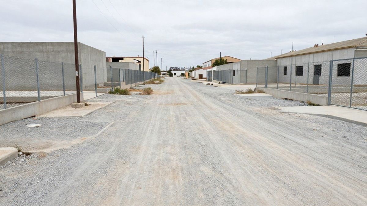 Illustrative image: an ordinary-looking industrial expanse, with metal fences and warehouses under construction against a cloudy sky