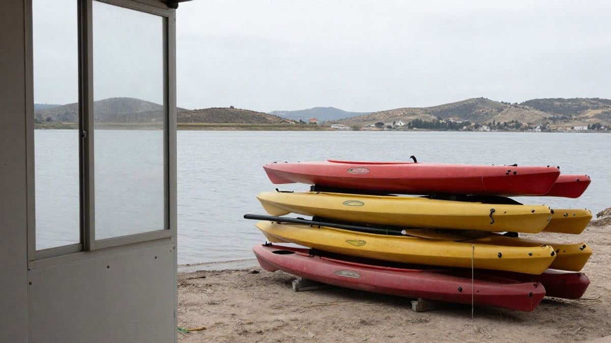 Illustrative image: kayaks and paddles on the shore of a calm reservoir with hills in the background