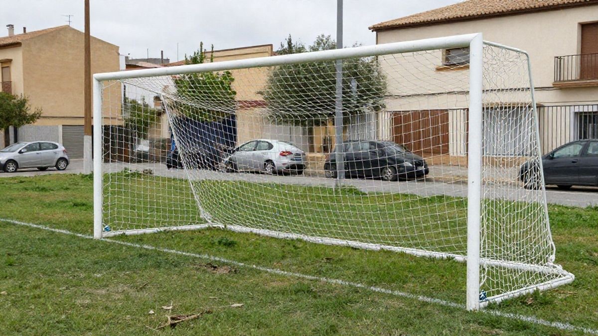 Imagen ilustrativa: una portería de fútbol con la red desgastada en un campo de hierba, vista desde la banda en un día nublado