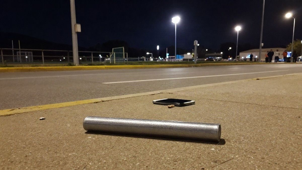 Illustrative image: relay baton and a mobile phone on the ground under streetlight at night