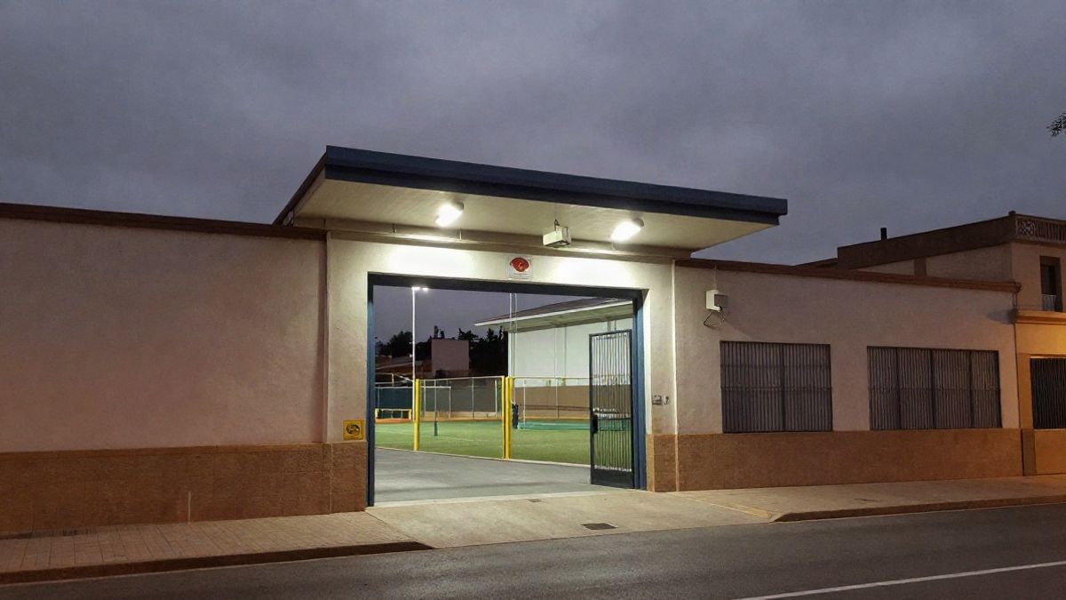 Imagen ilustrativa: entrada de un recinto deportivo genérico iluminada por focos nocturnos