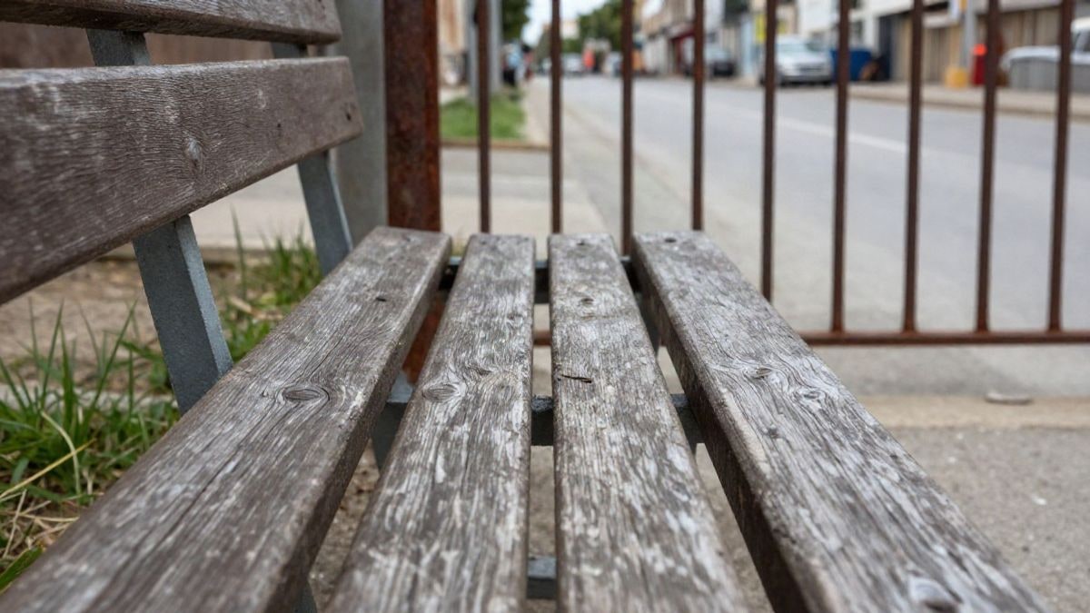 Imagen ilustrativa: detalle de un banco de madera gastado junto a una valla metálica oxidada en un campo de entrenamiento