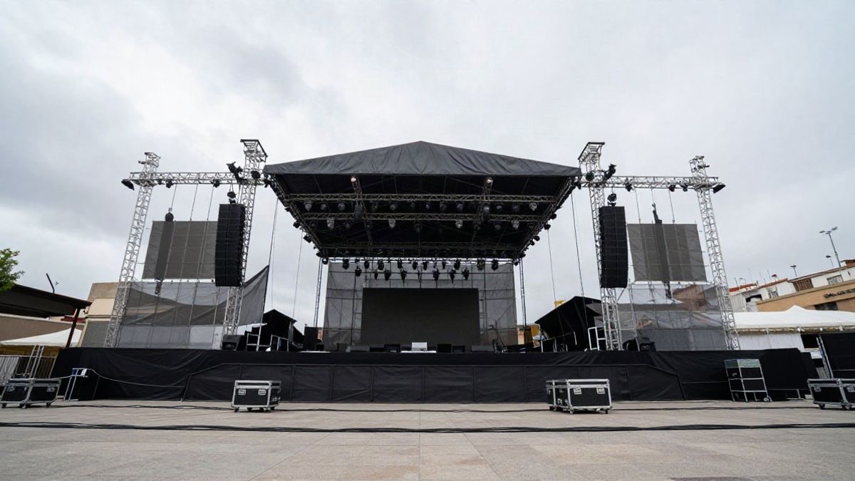 Imagen ilustrativa: escenario de concierto al aire libre visto desde el suelo con cielo nublado de fondo