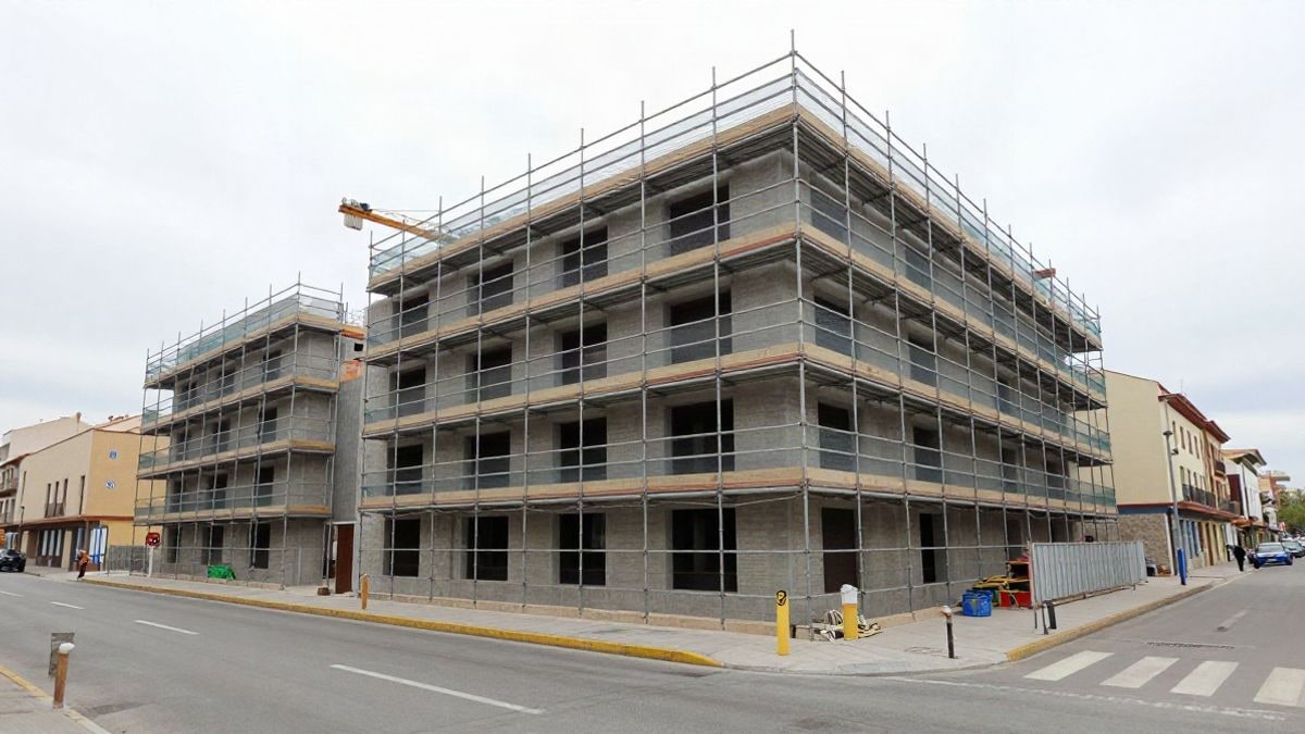 Imagen ilustrativa: edificio de viviendas en construcción con andamios, visto desde la calle en un día nublado