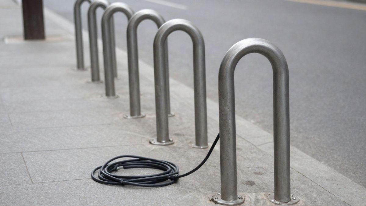Imagen ilustrativa: detalle de un aparcabicis metálico y un cable de recarga en la calle