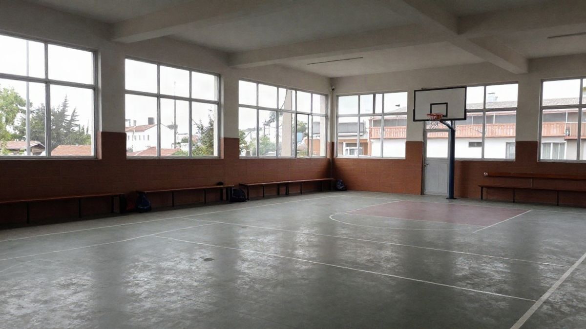 Imagen ilustrativa: patio escolar vacío con luz de ventana lateral y bancos junto a la pared